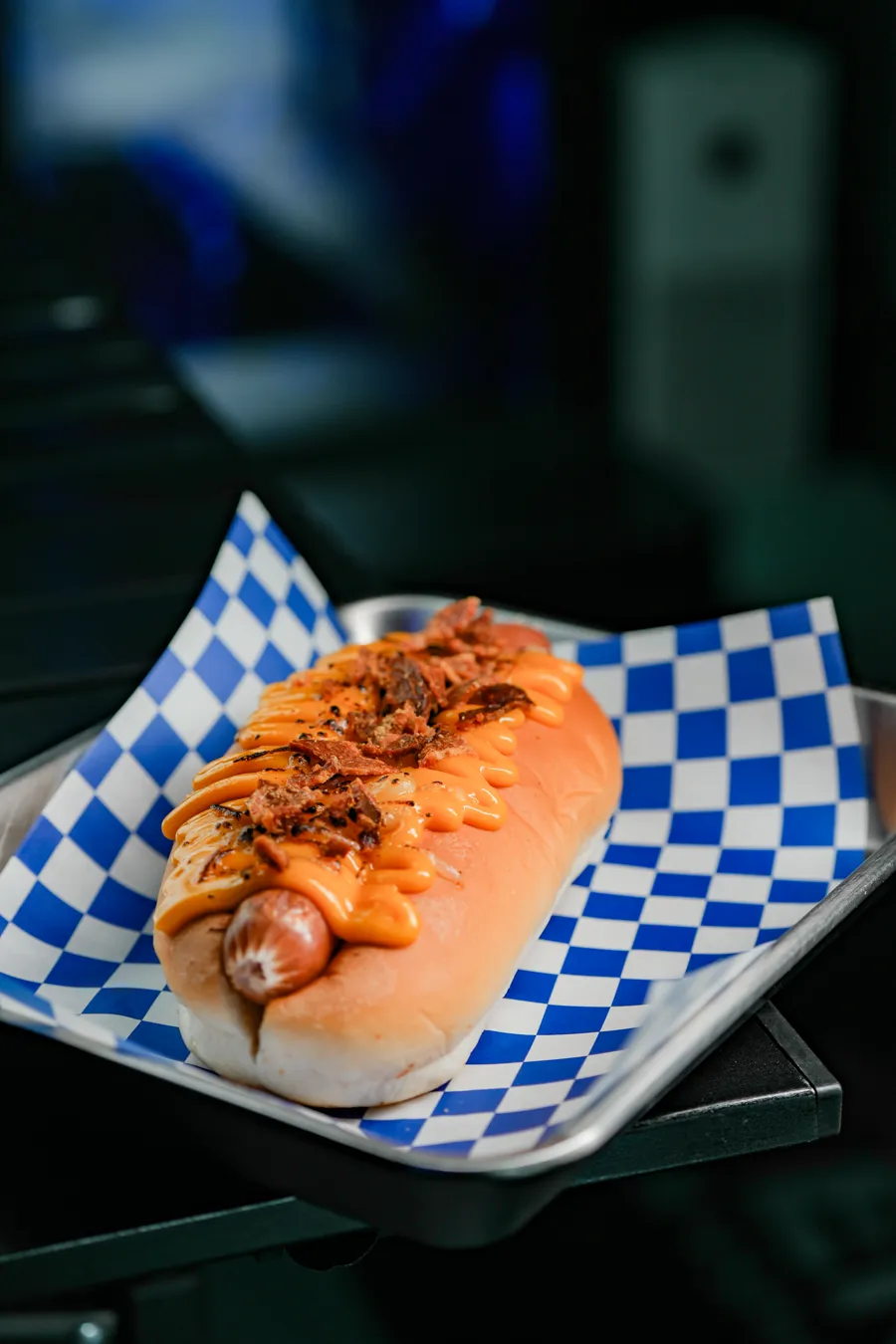 Hotdogray 熱狗菜單的炙燒培根起司熱狗，麵包夾香腸淋上起司醬、鋪滿培根碎，放在藍白格紋紙上