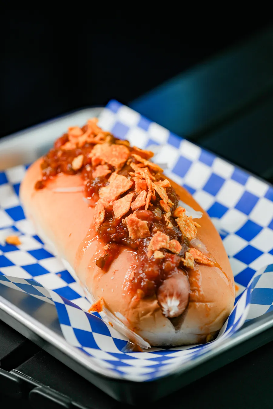 Hotdogray 熱狗菜單的肉醬熱狗，紅色肉醬淋在香腸上，鋪著碎脆片，放在藍白格紋紙上