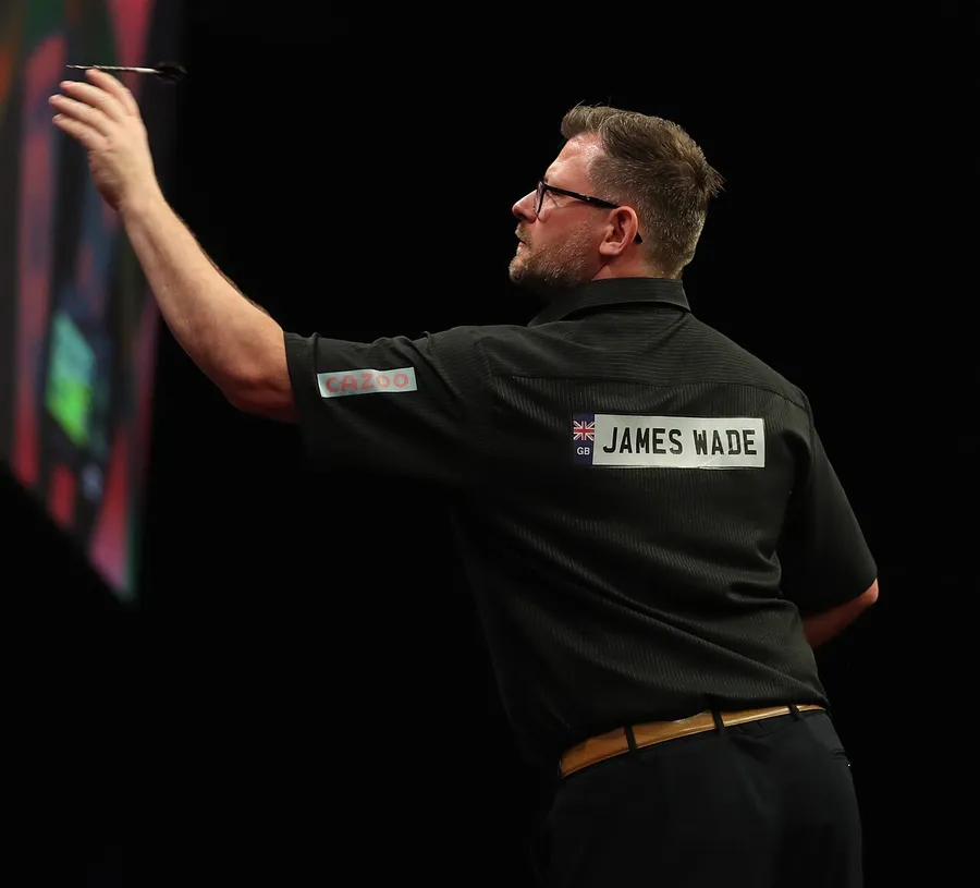 左撇子飛鏢選手 James Wade 背對鏡頭，舉起左手準備出鏢