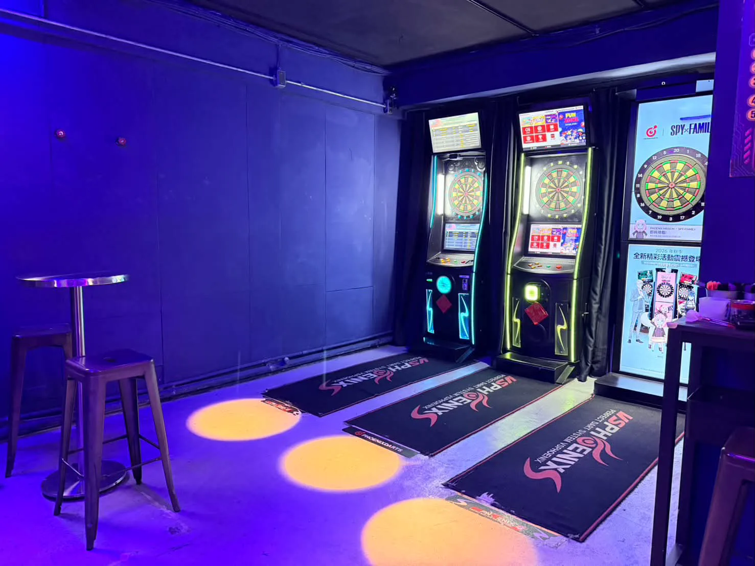 AI DARTS 店內並排的 Phoenix 電子飛鏢機台，地上鋪著機台地墊，左側有高腳桌與椅凳